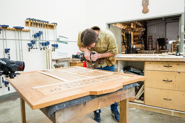 man drilling into wood working project in workshop