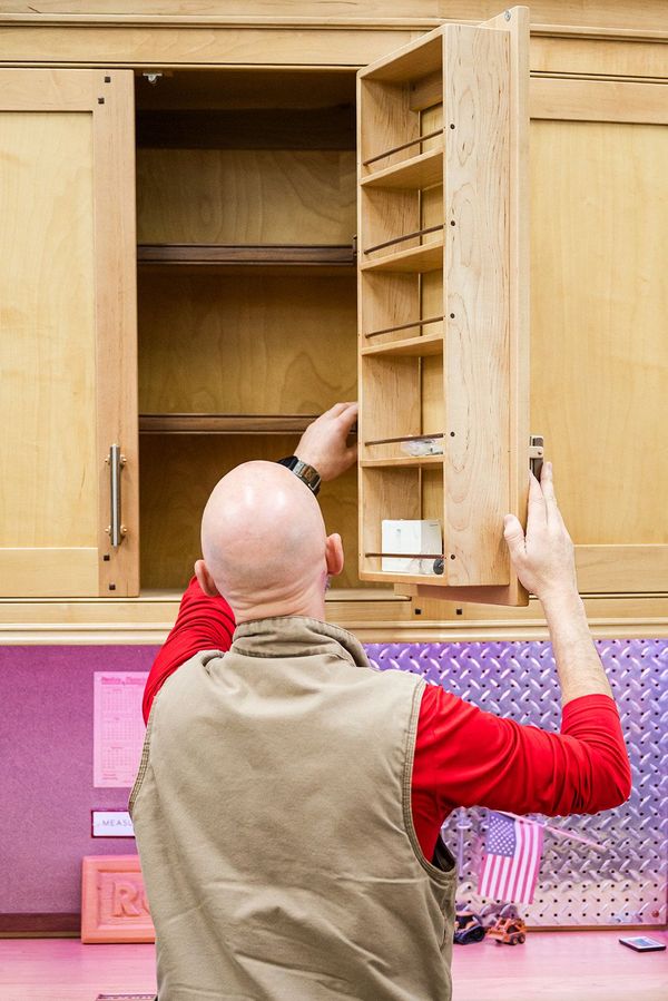 man checking inside upper cabinets of a workshop