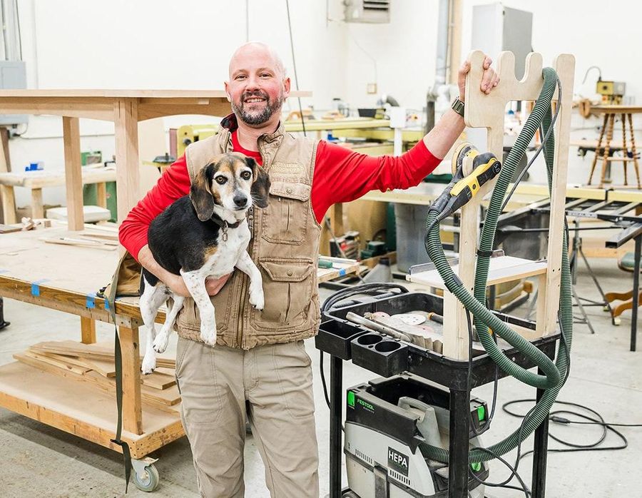 owner with his dog inside the wood working shop