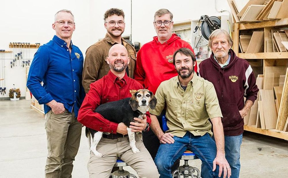 6 employees inside the wood shop with their dog
