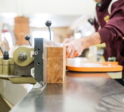showing hands cutting wood in a workshop