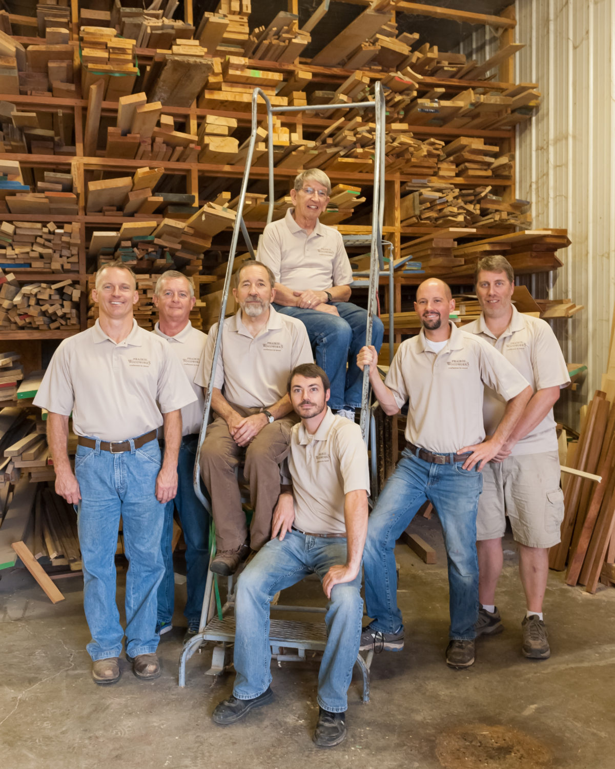 A group of men standing in front of stacks of wood.