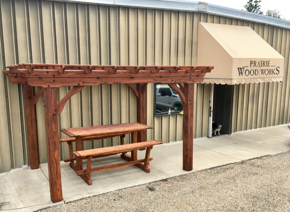 A wooden bench sitting under an arbor.