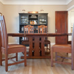 A dining room table and chairs in front of a china cabinet.