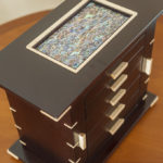 A wooden box with five drawers and two brass handles.